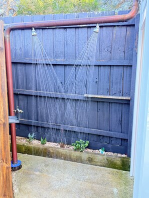 A wooden fence with a water spout and a concrete ground.