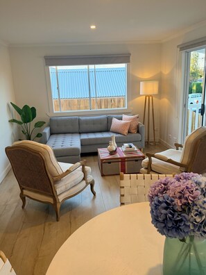 Una sala de estar con un sofá, dos sillones, una mesa de centro y una lámpara.