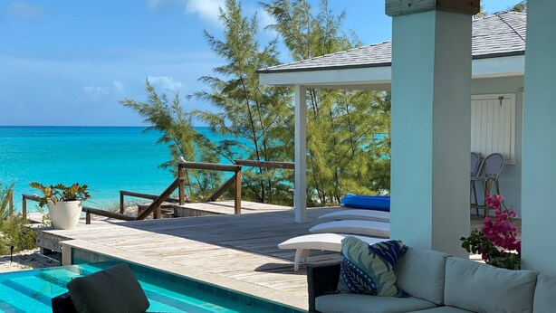 Une terrasse en bois avec une piscine, un espace salon extérieur et une vue sur l’océan.