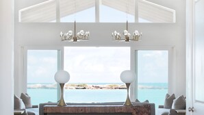 Un intérieur moderne avec un comptoir d’accueil en bois, un lustre et une vue sur la mer.