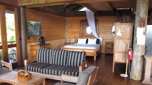 L’intérieur d’un chalet en bois comprend un lit, un canapé, un fauteuil et une table à manger.