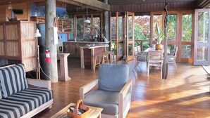 Un vaste espace de vie doté d’un plafond en bois, d’une cuisine avec un bar et de grandes fenêtres.