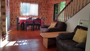 A living room with a dining area, brick walls, a staircase, and a window with blinds. - K'GARI (FRASER ISLAND) My Island Home. Sleeps 14. Situated in Eurong  (Eurong)