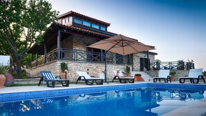 Una zona junto a la piscina con sillones de descanso y una pérgola.