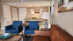 A living room with a brown sofa, two blue armchairs, a small wooden table, and a lamp.