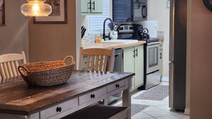 A kitchen with a wooden table, a woven basket, and a microwave.
