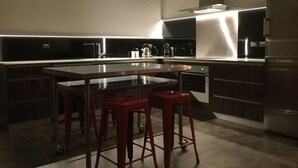 Eine moderne Küche mit Kochinsel, Edelstahlgeräten und roten Barhocker.