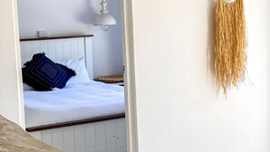 Un dormitorio con una cama, una lámpara colgante y un adorno de macramé en la pared.