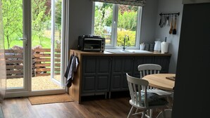 Una cocina con horno empotrado, lavamanos y comedor con mesa y sillas.