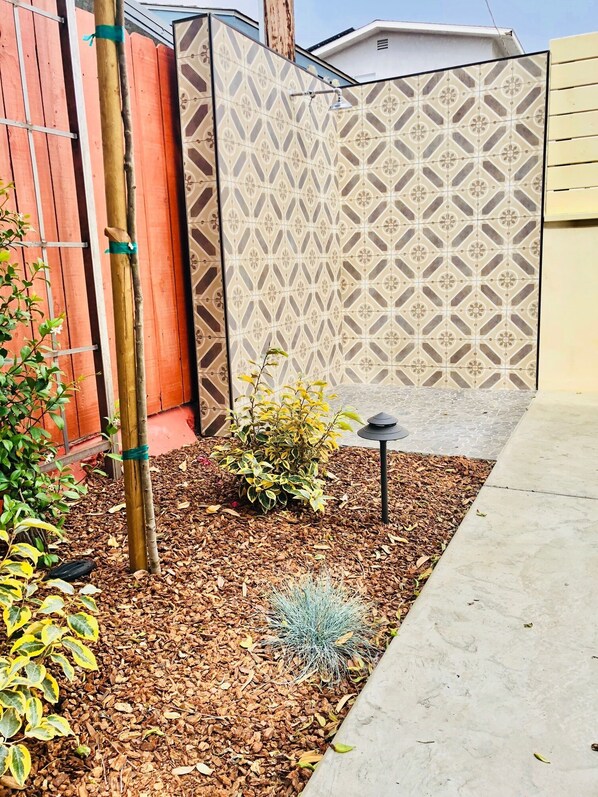 A garden area with mulch, a small bush, a cactus, and a decorative fence.