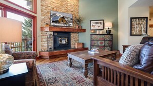 A cozy living room with a stone fireplace, a wooden coffee table, and a patterned rug. - RA208 | Nicely Appointed Condo | Quiet setting | Winter Shuttle | Wood Fireplace (Steamboat Springs)