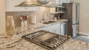 Una cocina moderna con estufa a gas, electrodomésticos de acero inoxidable y un salpicadero decorado.