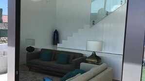 A modern living room with a sofa, a lamp, and a staircase.