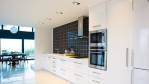 A modern kitchen with white cabinetry, a black tiled backsplash, and stainless steel appliances.