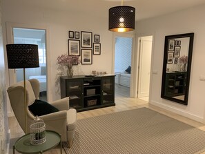 A modern living room with a sofa, a side table, a console table with framed pictures, a large mirror, and a hanging light fixture. - Apartment in Barrio de San Pedro (Santiago de Compostela)