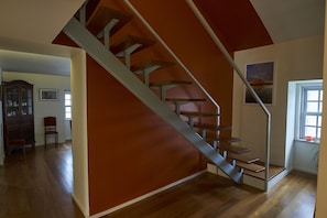 A staircase with a red accent wall, wooden steps, and a metal railing.