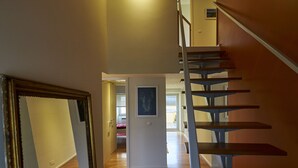 A staircase with a modern design, leading to an upper floor. A framed picture hangs on the wall at the top of the stairs. - Casa do Becco - with breathtaking views of the ocean and the historic center (Angra do Heroísmo)