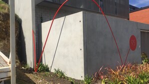 A modern building with a concrete facade, a red circular logo, and a number '95' on the side.