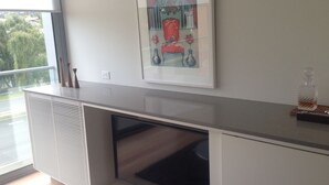 A modern kitchen with a built-in oven, a window with blinds, and a decorative piece on the wall.