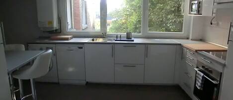 Een moderne keuken met een raam, roestvrijstalen apparatuur en een barkruk.