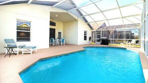 En indendørs swimmingpool med glaslofter, liggestole og en overdækket patio.