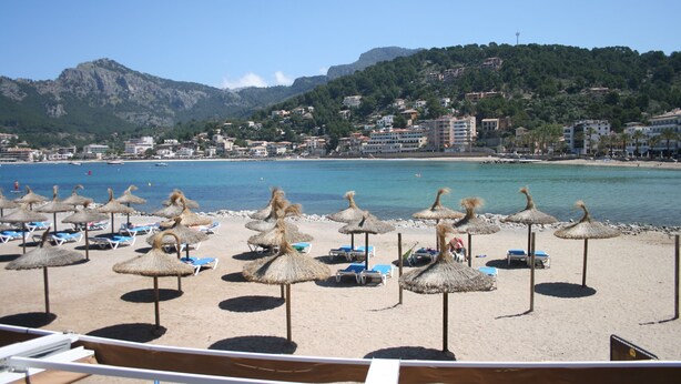 A beach with thatched umbrellas and sun loungers, a clear view of the sea, and buildings in the background. - Stunning, romantic 1 Bedroom Property With Terrace (Fornalutx)