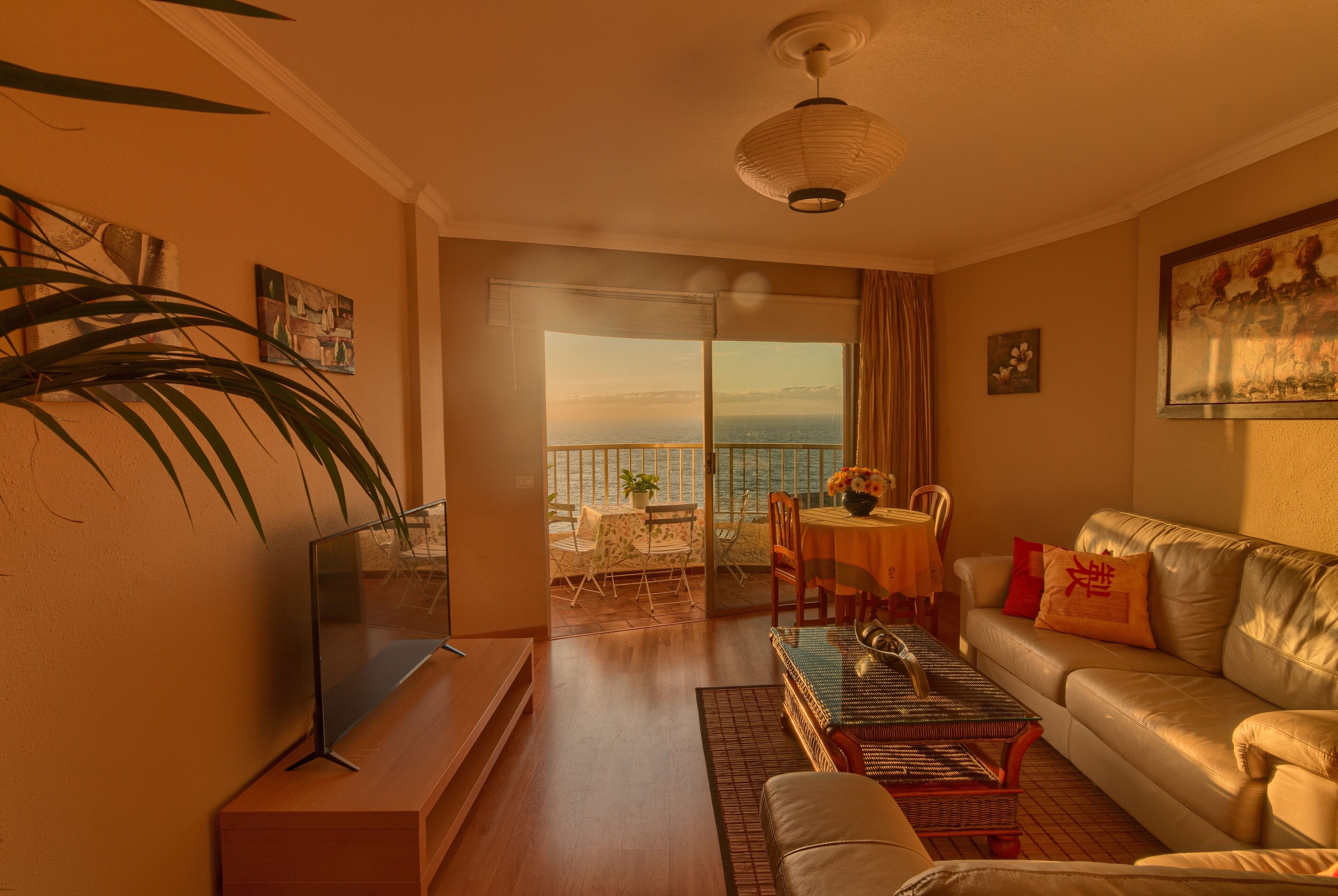 A living room with a sofa, coffee table, TV, and a balcony with a view.