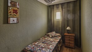 Une petite pièce agréable, dotée d’un lit simple, d’une table de chevet en bois, d’une lampe et d’un tableau accroché au mur.