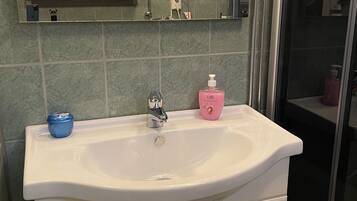 Un bagno con lavandino bianco, uno specchio e zona doccia.