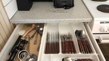 Un cajón de cocina con utensilios y una cafetera sobre la encimera.