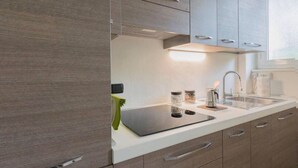 A modern kitchen with wooden cabinets, a white countertop, and stainless steel appliances. - Relax and stand a few steps away from the city center (Milano)