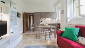 A compact living space with a kitchen, dining area, and a red sofa with green cushions. - Relax and stand a few steps away from the city center (Milano)