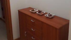 Una habitación con un armario de madera, dos adornos colgantes en la pared y un enchufe.
