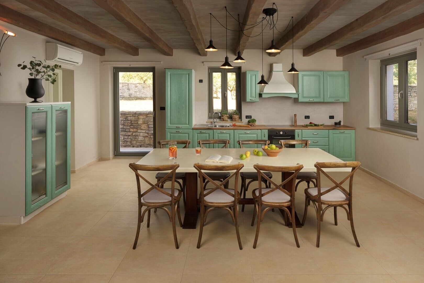 Una cocina amplia con armarios azul verdosos, una isla grande y sillas de madera.