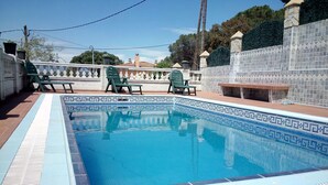 Une piscine rectangulaire dont le bord est recouvert de carreaux, et qui est entourée d’un petit muret.
