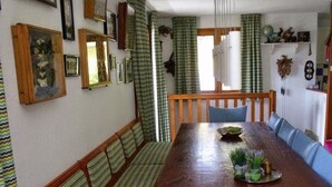 Ein Essbereich mit einem langen Holztisch, Bänken und einer Chandelüster.
