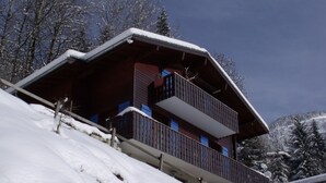 Eine Holzhütte mit Balkon und schneebedecktem Dach.