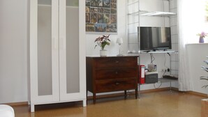 A room with a white wardrobe, a wooden dresser, a TV on a stand, and a poster on the wall. - Quiet non-smoking vacation apartment w beautiful garden in Freiburg-Gundelfingen (Gundelfingen)