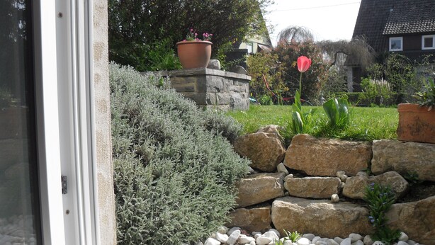 A garden with a stone wall, white pebbles, and various plants. - Quiet non-smoking vacation apartment w beautiful garden in Freiburg-Gundelfingen (Gundelfingen)