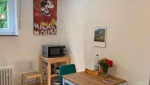 A small dining area with a wooden table and green chairs, a microwave, a radiator, and a Mickey Mouse poster on the wall. - Quiet non-smoking vacation apartment w beautiful garden in Freiburg-Gundelfingen (Gundelfingen)