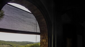 Une fenêtre donnant sur un paysage verdoyant et un mur de briques.