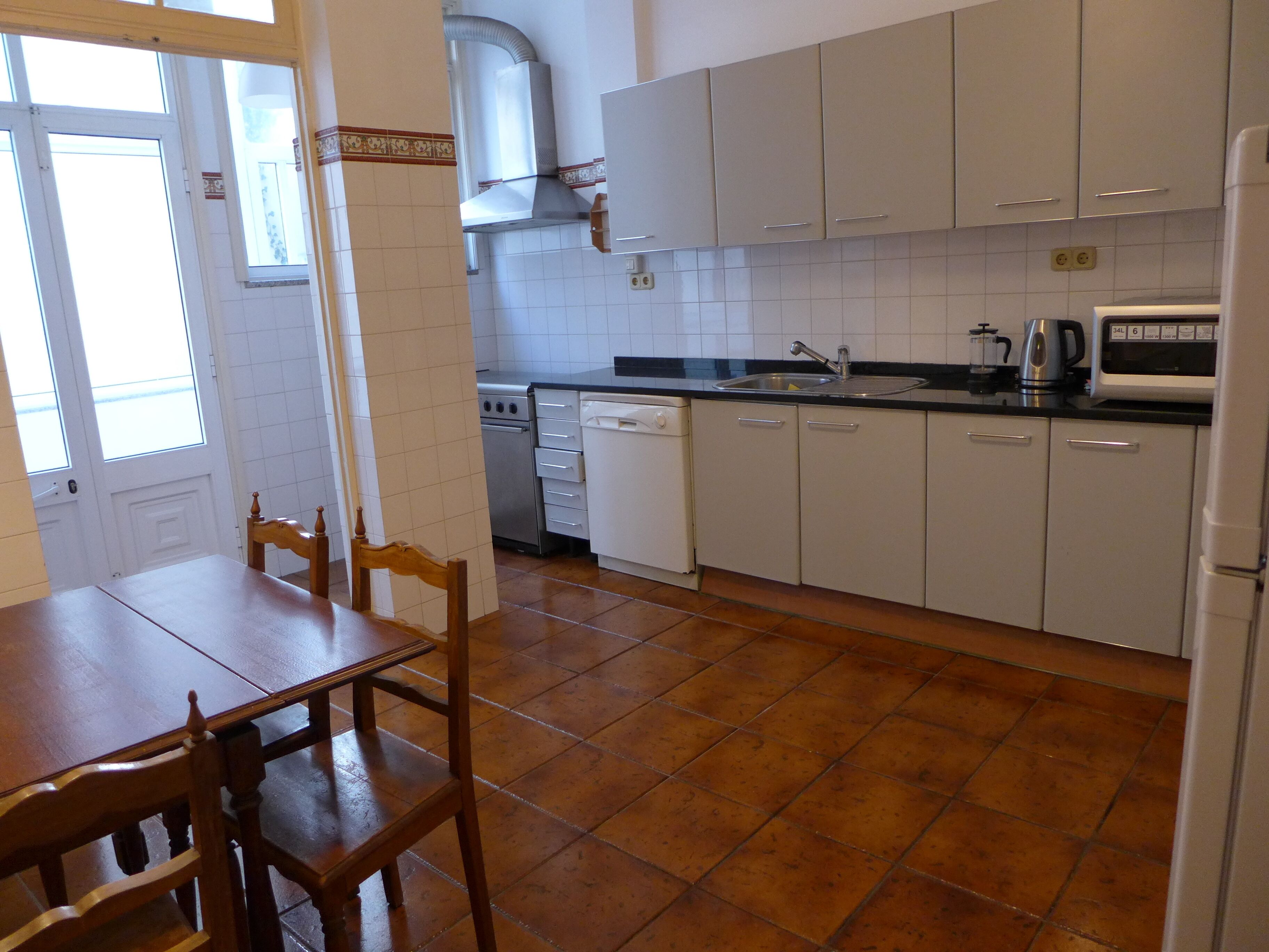 A kitchen with white cabinets, a stove, a sink, and a microwave.