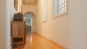 A hallway with wooden flooring, a wooden cabinet, and a large window with bars. - Carolina M Apt in front of Metro (Porto)