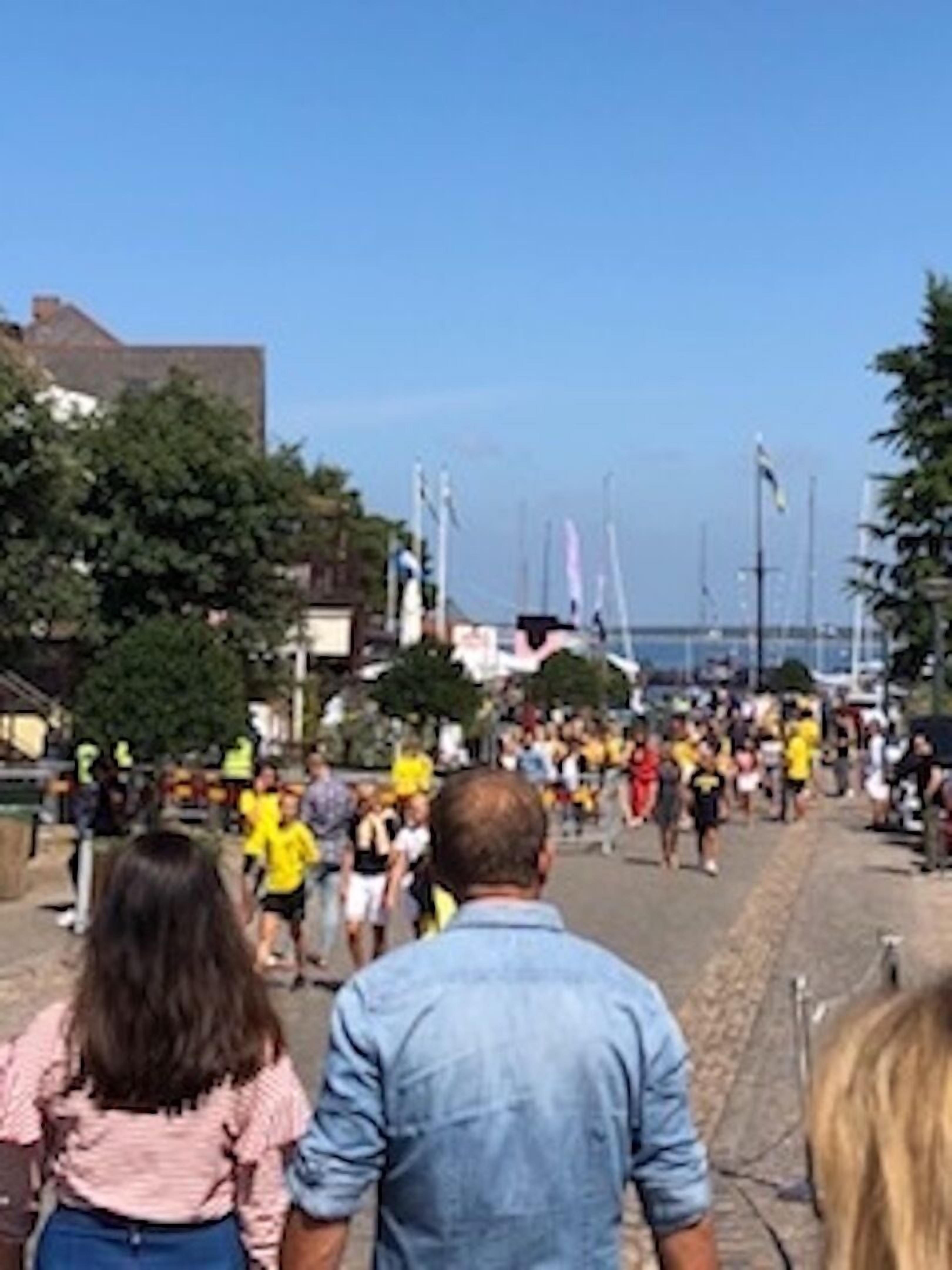 A crowded street with people walking, some in yellow shirts.