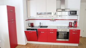 A modern kitchen with red and white cabinetry, stainless steel appliances, and a tiled backsplash. - Lake Constance, Friedrichshafen, central location, 2 people (Friedrichshafen)