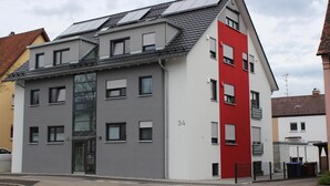 A modern multi-story building with a grey facade and a red accent wall. - Lake Constance, Friedrichshafen, central location, 2 people (Friedrichshafen)