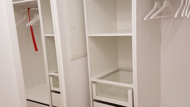 A white walk-in closet with multiple shelves, drawers, and hanging space. - Lake Constance, Friedrichshafen, central location, 2 people (Friedrichshafen)