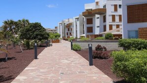 A pathway leading to a row of modern buildings with balconies and a clear sky.