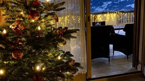 Un árbol de Navidad con luces y adornos en una habitación con vistas a montañas nevadas.