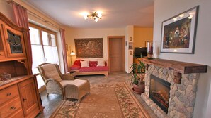 Una sala de estar acogedora con chimenea, un sofá, un sillón y un cuadro grande en la pared.